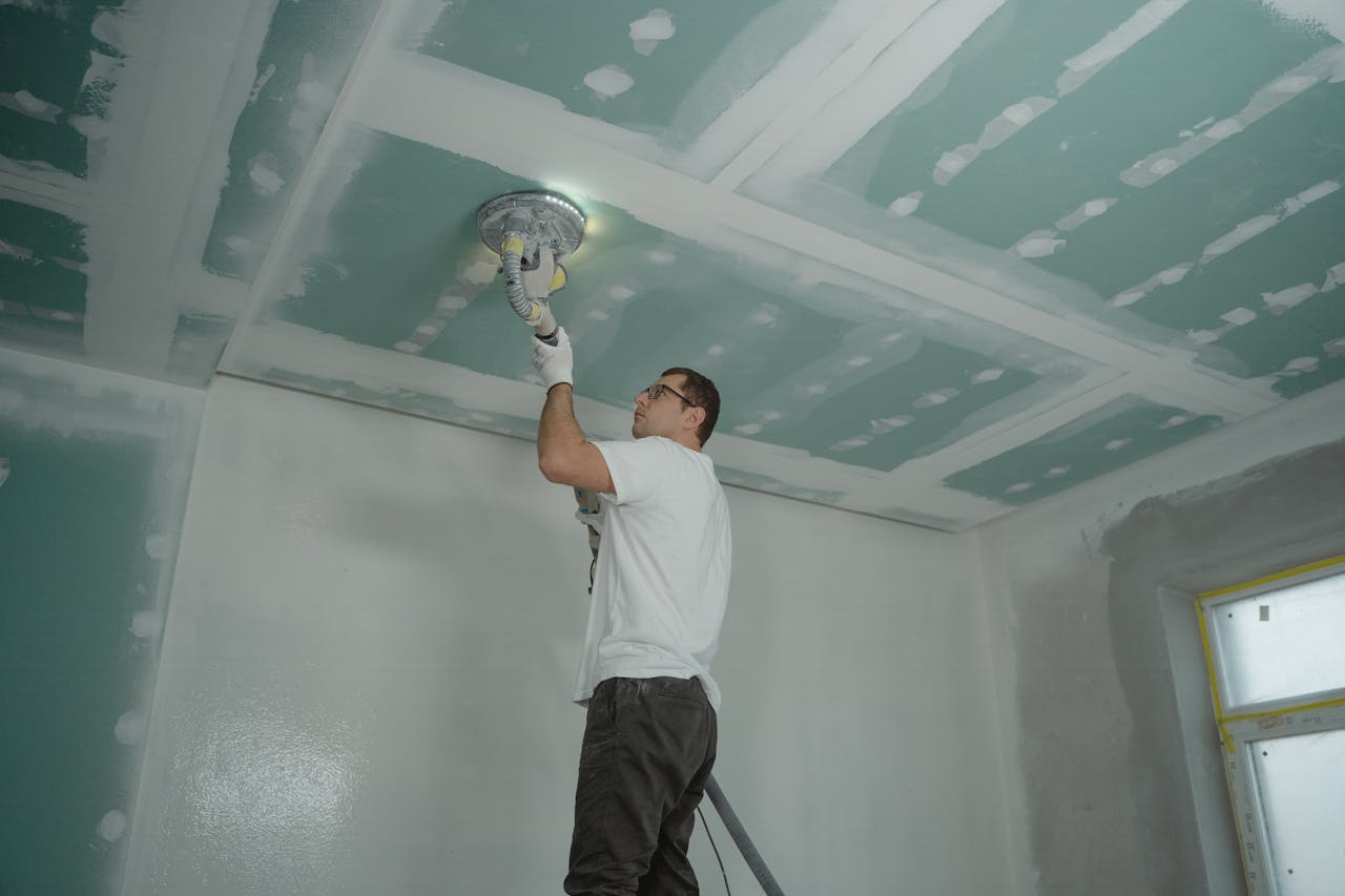 A worker expertly polishes a ceiling indoors, demonstrating home renovation skills.